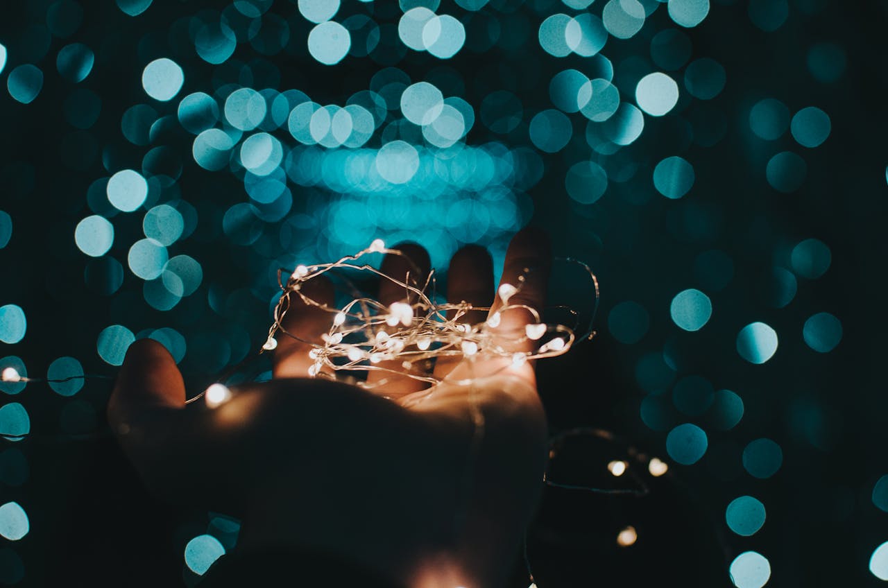 A mesmerizing shot of string lights glowing softly in a hand against a bokeh background.